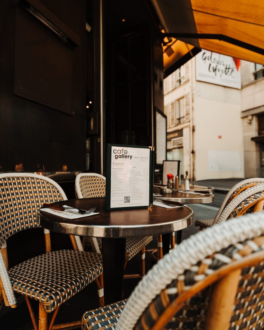 Table de la terrasse du Café Gallery avec la carte de l'apéritif, chaises en rotin tressé