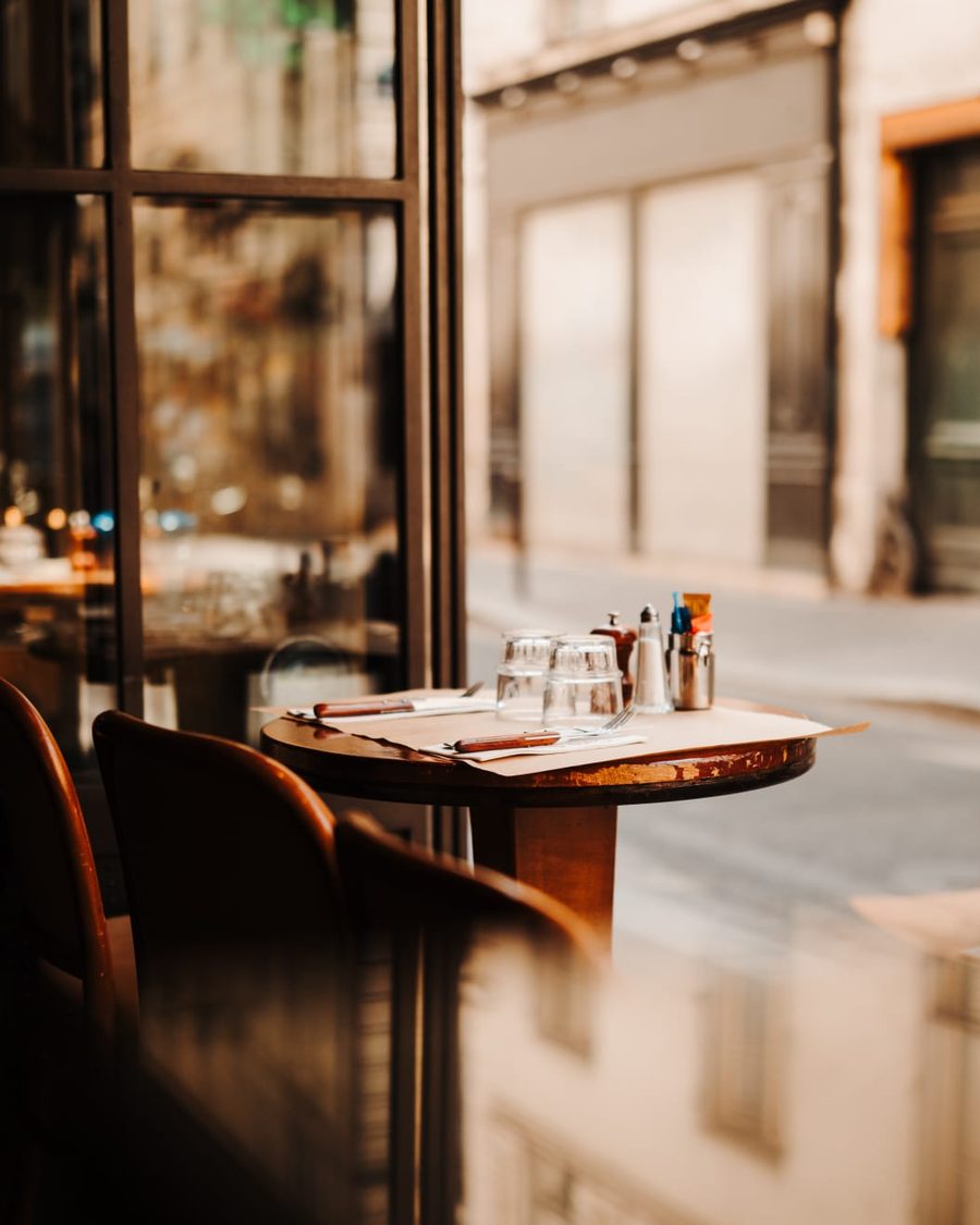 Table de bistrot dressée près de la fenêtre au petit matin, verres retournés et moulin à poivre