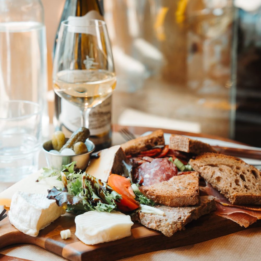 Planche de charcuterie et fromages du Café Gallery sur planche en bois : jambon sec, saucisson, brie, cornichons et pain de campagne