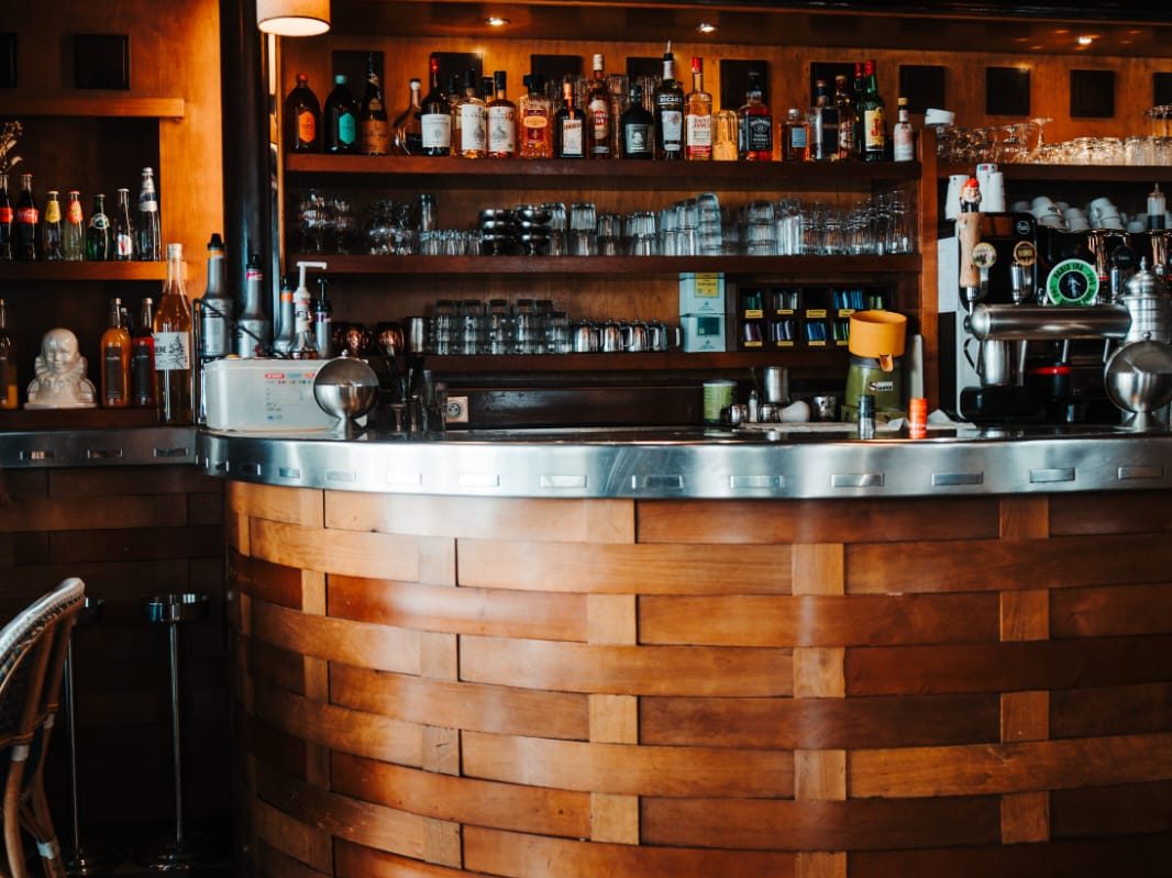 Comptoir arrondi en bois tressé et plateau de zinc du Café Gallery, étagères de bouteilles et machine à café