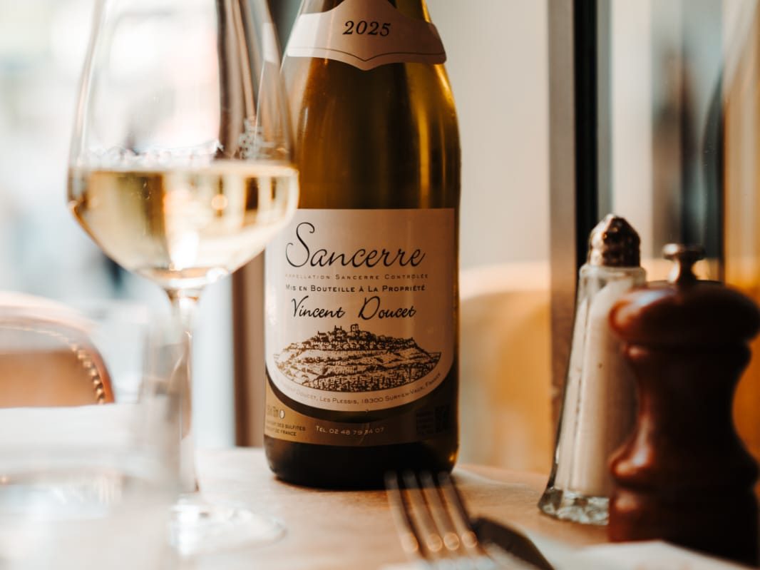 Bouteille de Sancerre blanc et verre servi sur une table du Café Gallery, près de la vitrine